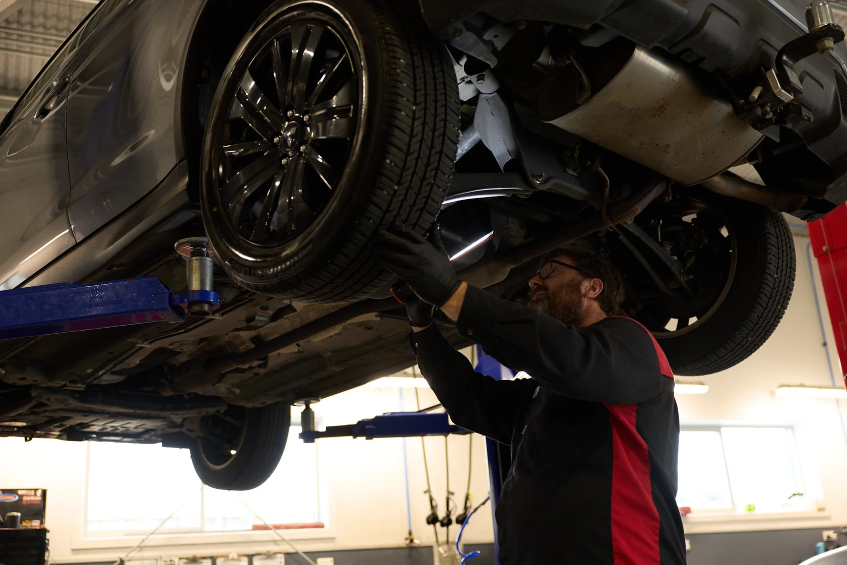 Mitsubishi dealer technician inspecting the underside of a vehicle on a hoist
